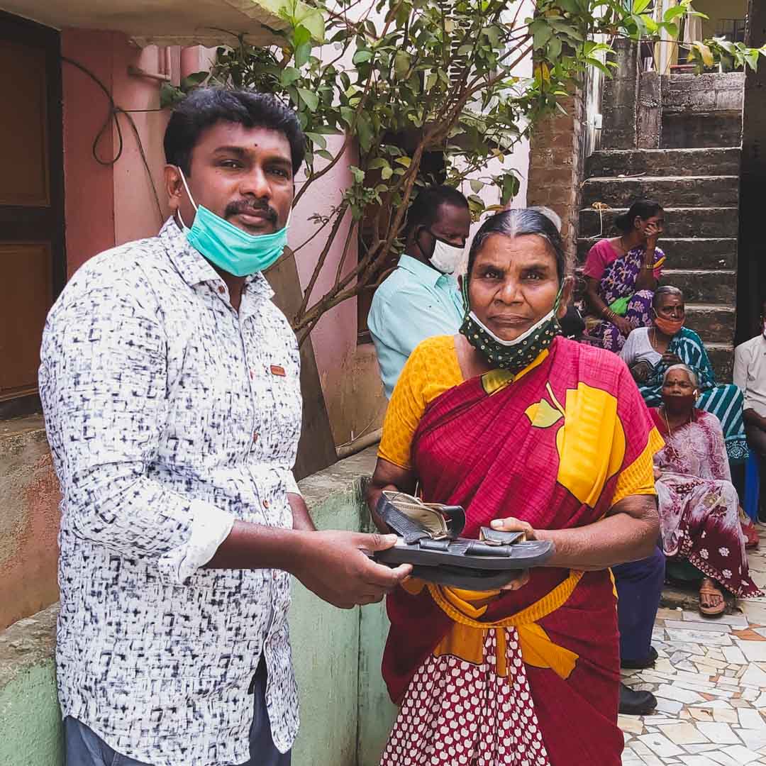 a man hands a pair of shoes to a woman at embrace a village
